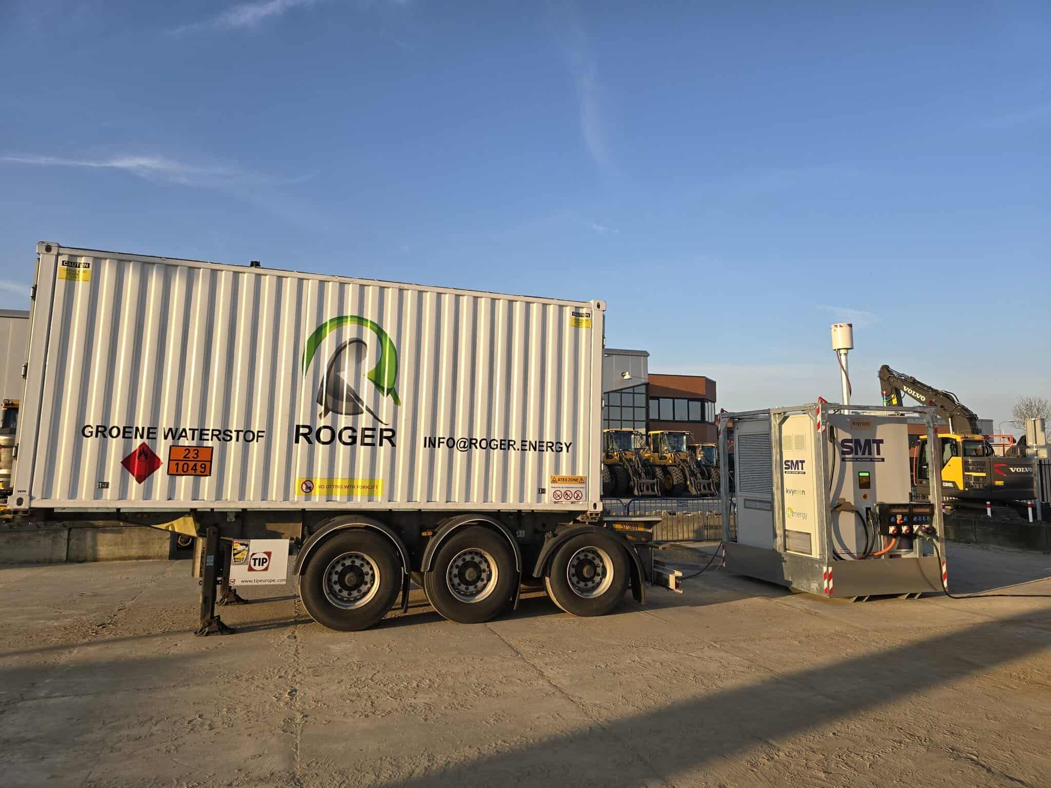 A white container labeled "Roger" is mounted on a trailer next to an SMT-branded unit in an industrial yard with machinery and a building in the background.