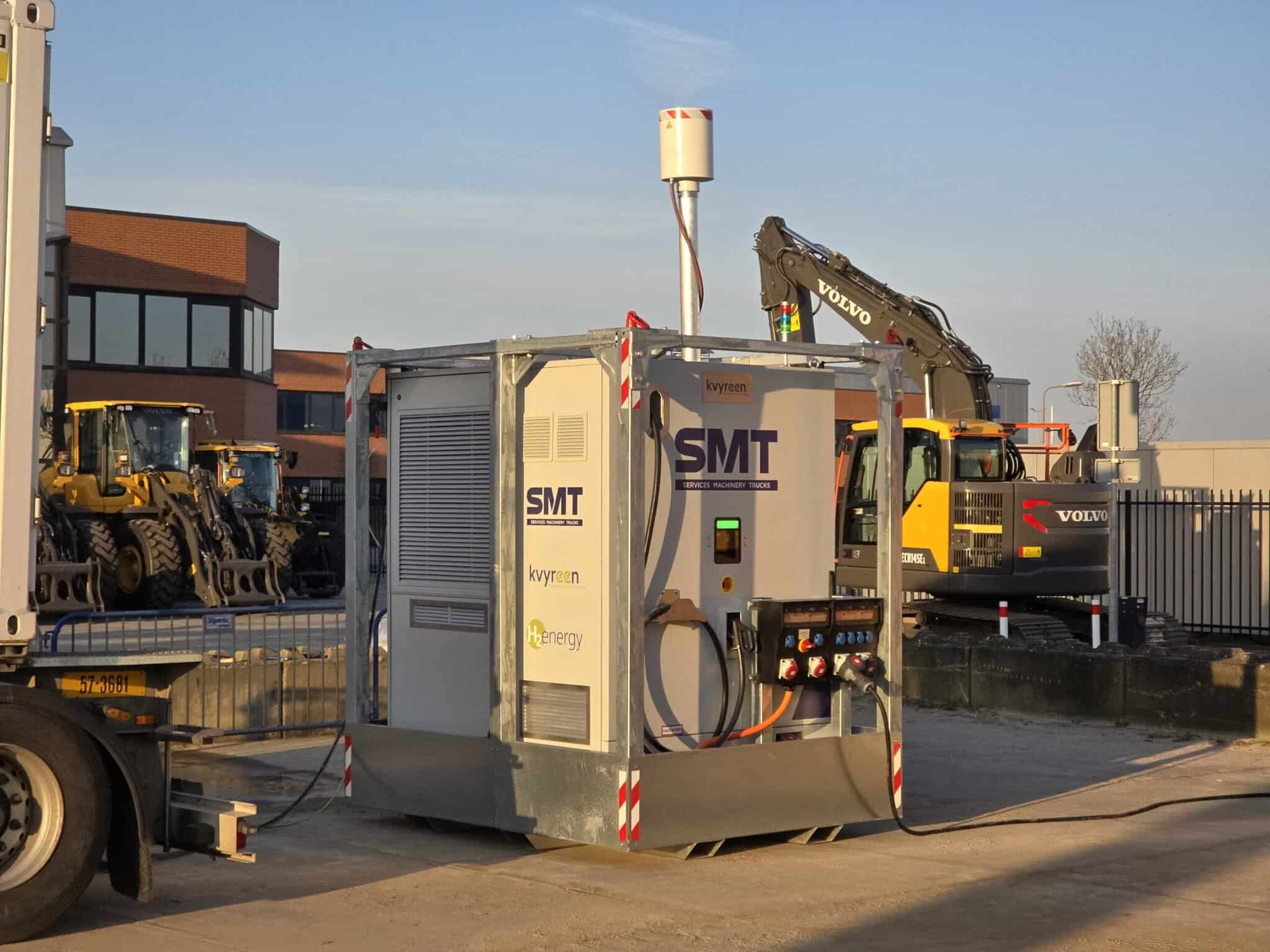 A portable industrial unit labeled SMT is set up at a construction site, with excavators and loaders in the background.